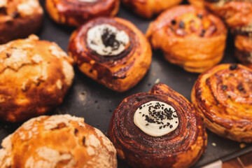 Pastry, selection assortment variety of different bakery, with cinnamon bun, croissant, swiss rolls, cake, eclair and others in a basket or a plate, baked desserts, catering or cafe banquet table