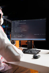 Muslim guy sits at desk and codes on computer, demonstrating the app development process....