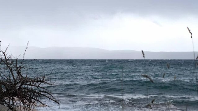 Beautiful rain curtain above the disquiet wavy sea surface. Stormy weather one day after Storm Ciar&aacute;n smashed into Krk Island with strong winds and driving rain.