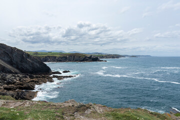 a serene coastal landscape with rocky cliffs, turbulent ocean waves, and a cloudy sky, creating a dynamic atmosphere