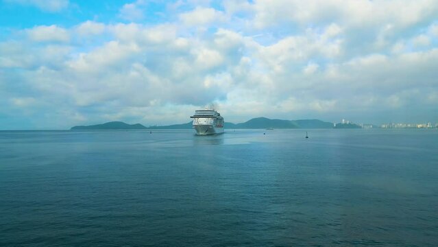 Cruise liner sailing. People on the upper deck celebrates vacation. 4K aerial view of shipboard of the cruise ship leaving terminal. Water transportation.
