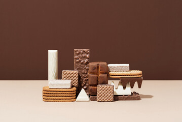 Sweets still life. Composition of sweets: biscuit, candy bar, chocolate, cookie and waffle on a beige and brown background. Minimalist composition in neutral colors