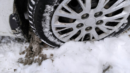Dirty messy snow near car wheel. Mud, salt and chemicals on winter road. Ecology problem in city....