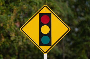Traffic light warning sign on green nature.