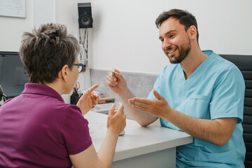 Otolaryngologist showing Modern miniature hearing aids for mid aged woman at modern medical center....