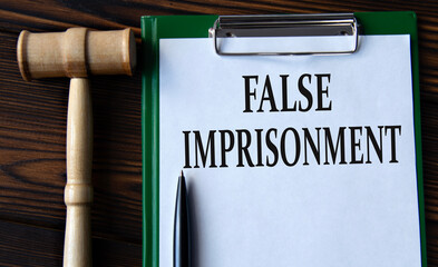 FALSE IMPRISONMENT - words on a white sheet with a judge's gavel - obrazy, fototapety, plakaty