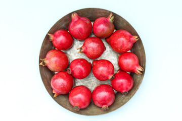 Pomegranate fruits in a plate on white background top view 