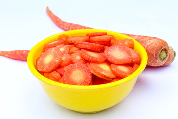 Sliced Carrots in a bowl on white background close-up view 
