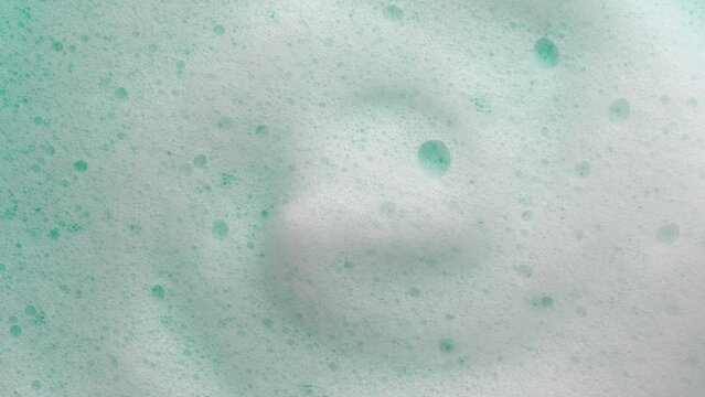 Foam backdrop on blue background. Liquid soap bubbles, Froth bubbles backdrop. Soap foam popping bubble rotating, white backdrop. Soap sud macro structure close-up. Clean, cleaning, washing, laundry