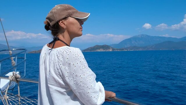 Resting woman on boat against ocean. A nice woman in cap relax on the deck during yacht floating against blue sea waves.