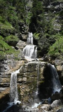 Slow motion of a threefold waterfall in summer, vertical shot
