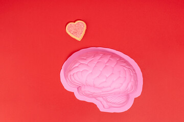 Brain in love concept flat lay still life of pink brain and sparkling red hearts on red background