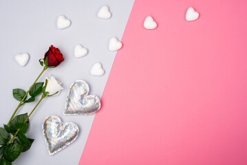 Romantic pink and grey background with white and red roses with small white foam hearts and silver...
