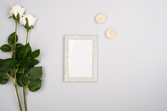 romantic gray background with empty frame in the center with two white roses with candles