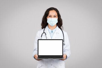 Doctor woman with mask presenting white laptop screen