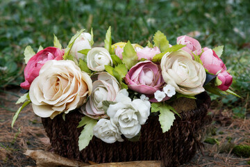 a basket of pastel-colored faded artificial roses on a grave in a cemetery
