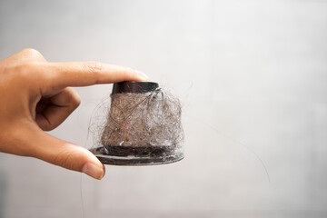 Dirty paper filter of a handheld vacuum cleaner. A man holds a cone filter with dust and hair in a...
