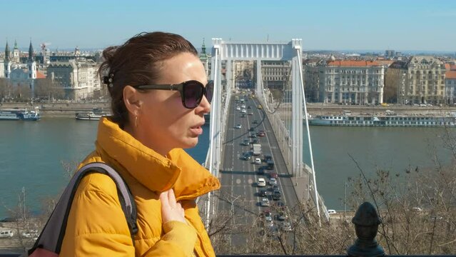 Female with asthma by city. A view of sick female suffer from asthma and use and inhaler against cityscape.