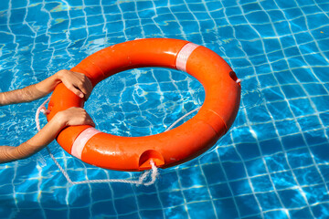 Lifeguard girl training with a life preserver swimming in the pool