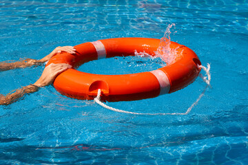 Lifeguard girl training with a life preserver swimming in the pool