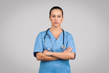 Stern nurse with arms crossed in scrubs