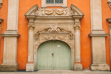 Carved wooden old green door in Gdansk.Orange wall with antique decor of columns. High quality photo