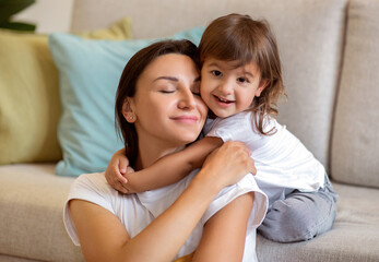 Mother's Day Concept. Cute Little Girl Embracing Her Mom At Home