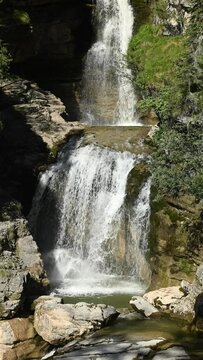 The middle part of a threefold waterfall with a pond, vertical shot