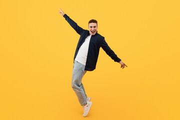 Cheerful young stylish caucasian guy moving on yellow background