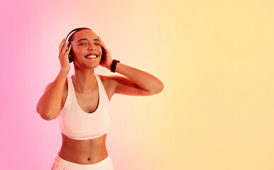 Euphoric woman with a buzz cut enjoying music on headphones, wearing a white sports bra