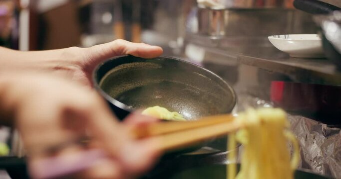 Cooking, restaurant and person with noodles at market for street food for meal preparation, eating and nutrition. Japan, flame and closeup of chopsticks for ramen lunch, cuisine dinner and supper