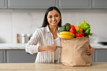 Young Woman Unpacking Paper Bag With Fresh Vegetables And Fruits