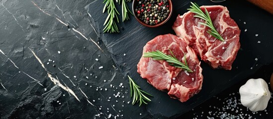 Raw organic meat beef or lamb on a black slate board Top view with copy space. with copy space image. Place for adding text or design - obrazy, fototapety, plakaty