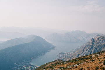 Fototapeta na wymiar View from the mountain of the valley of the Bay of Kotor surrounded by a mountain range in a light haze. Montenegro