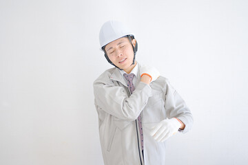 肩を回す作業着の男性