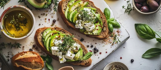 Gordijnen Open sandwich made of slices of sourdough bread with avocado feta cheese kalamata olives olive oil and oregano on a wooden white table close up Vegetarian food. with copy space image © vxnaghiyev