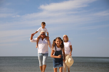 Cute little children with grandparents spending time together near sea