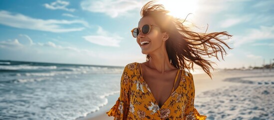 stylish attractive slim smiling woman on beach in summer style fashion trend outfit carefree and happy feeling freedom wearing yellow printed dress boho style chic and sunglasses