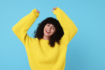Happy young woman in stylish yellow sweater on light blue background - Powered by Adobe