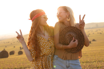 Beautiful happy hippie women showing peace signs in field