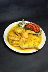 Balinese Indonesian food, Ayam Betutu. Whole chicken filled with Balinese seasoning cassava leaves, wrapped in banana leaves and steamed. Served with Sambal Matah and Roasted Peanuts.