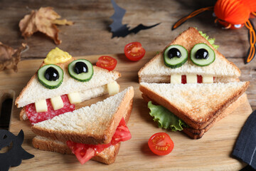 Cute monster sandwiches served on wooden board, closeup. Halloween party food