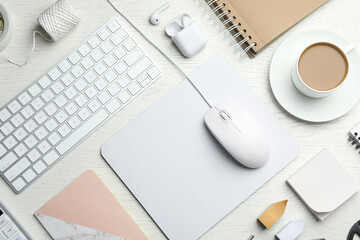 Flat lay composition with wired computer mouse, keyboard and stationery on white wooden table