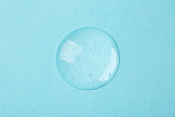 Sample of cosmetic serum on light blue background, top view