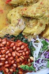 Balinese Indonesian food, Ayam Betutu. Whole chicken filled with Balinese seasoning cassava leaves, wrapped in banana leaves and steamed. Served with Sambal Matah and Roasted Peanuts.
