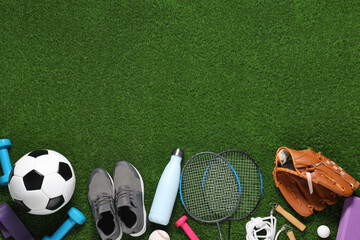 Different sports equipment on green grass, flat lay. Space for text