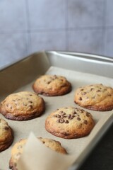 Baking pan with chocolate chip cookies on light background, closeup