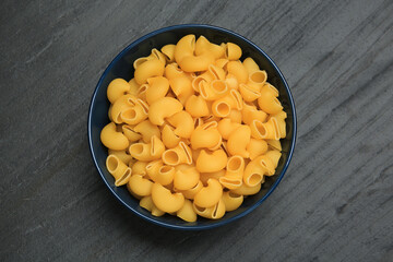 Raw macaroni pasta in bowl on grey table, top view