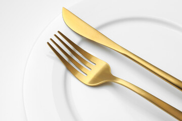 Clean plate, fork and knife on white background, closeup