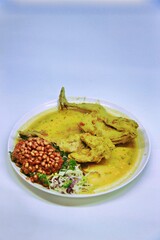 Balinese Indonesian food, Ayam Betutu. Whole chicken filled with Balinese seasoning cassava leaves, wrapped in banana leaves and steamed. Served with Sambal Matah and Roasted Peanuts.